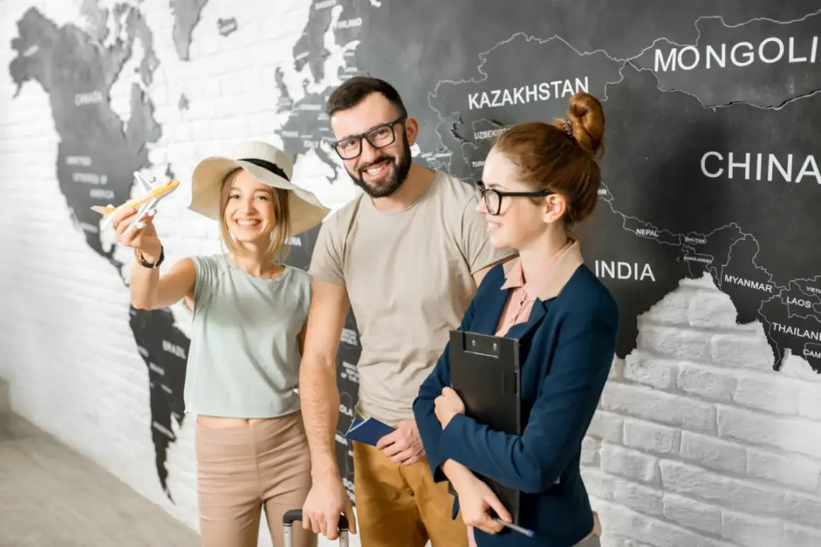 Para z paszportem i modelką samolotu przed mapą świata, obok pracownicy biura podróży.